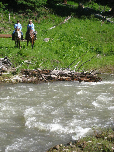 Dean Genge and Nancy Brown ride horseback along a Gallatin River tributary at the Club at Spanish Peaks in Big Sky, Montana