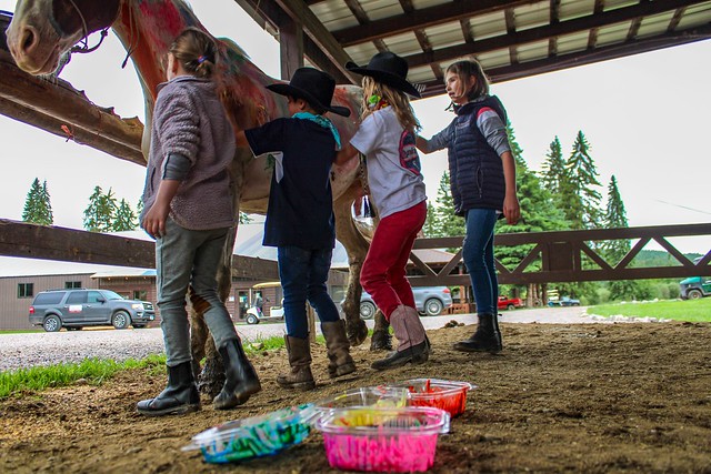 Four children get their hands covered in paint as a patient horse stands by to be the living art canvas.